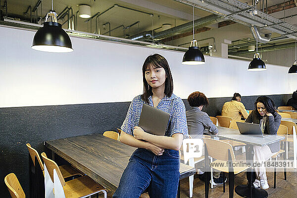 Young businesswoman with laptop sitting at table in office