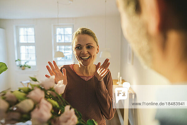 Surprised woman looking at flowers in living room