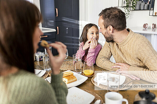 Happy girl with father having breakfast at dining table