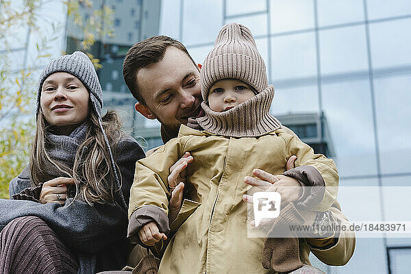 Lächelnde Frau mit Vater und Sohn vor dem Gebäude