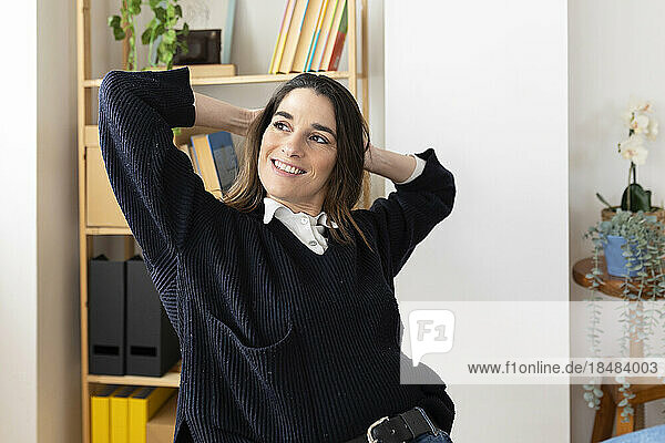 Happy businesswoman with hands behind head in office