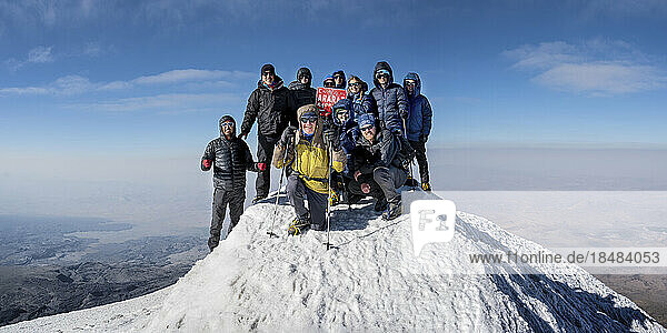 Wanderfreunde auf einem schneebedeckten Berg vor dem Himmel an einem sonnigen Tag