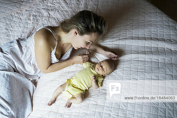 Mother spending leisure time with baby boy lying on bed