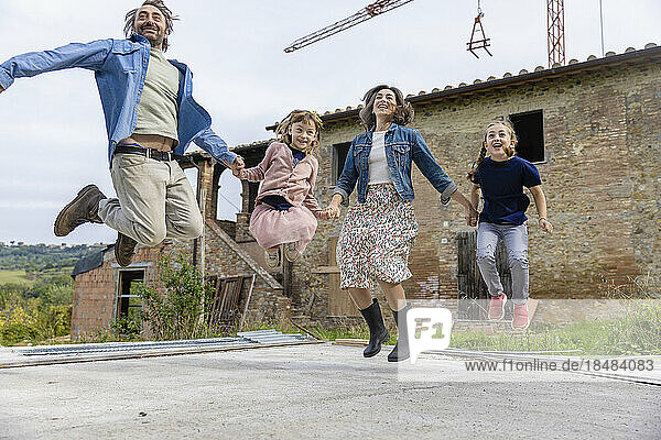 Cheerful family jumping in front of house