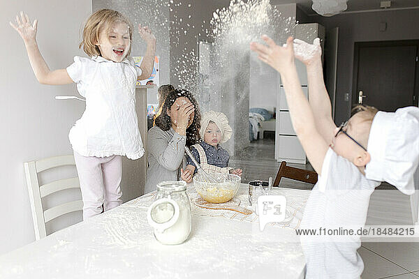 Playful children enjoying with flour in kitchen