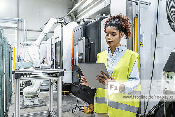 Engineer using tablet PC by machine in factory