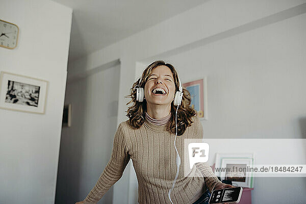 Happy woman wearing headphones listening to music at home