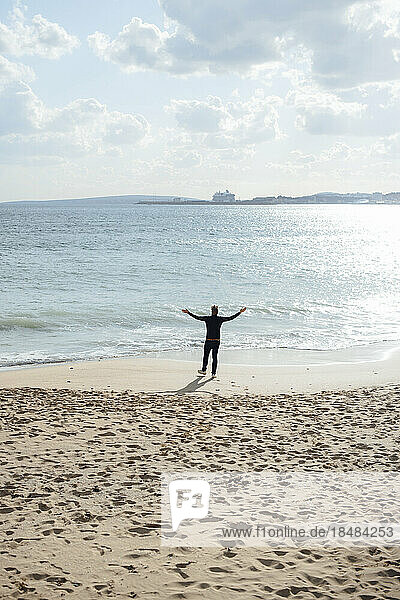 Man standing with arms outstretched at coastline