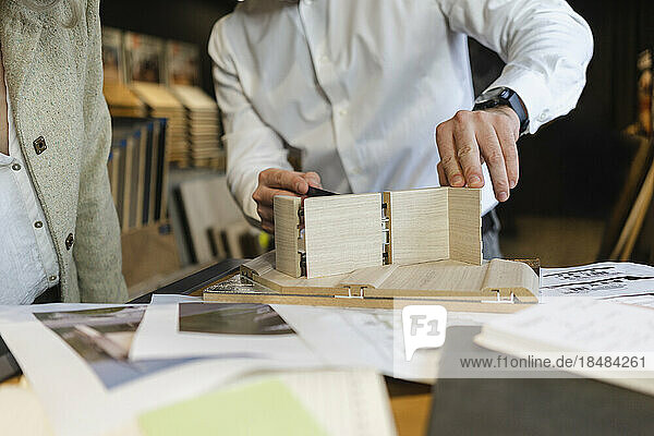 Nahaufnahme eines Mannes  der im Architekturbüro an einem Holzmodell arbeitet