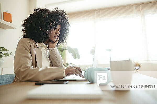 Junge Geschäftsfrau mit Afro-Frisur benutzt Laptop im Büro