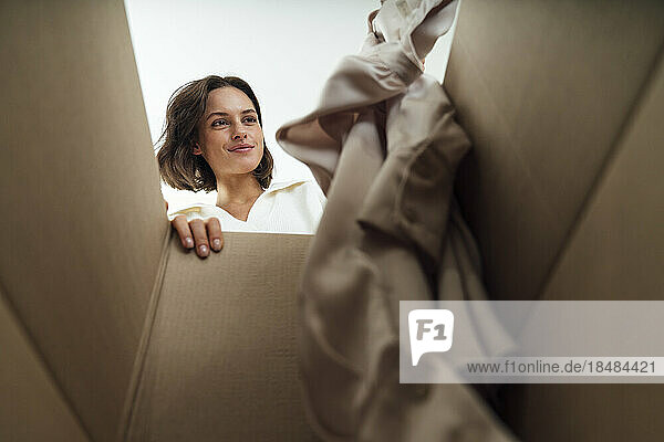Smiling woman putting clothes in box