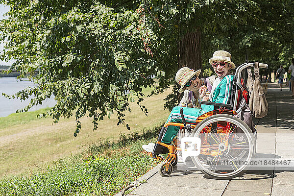 Happy woman looking at daughter with disability enjoying at sunny day