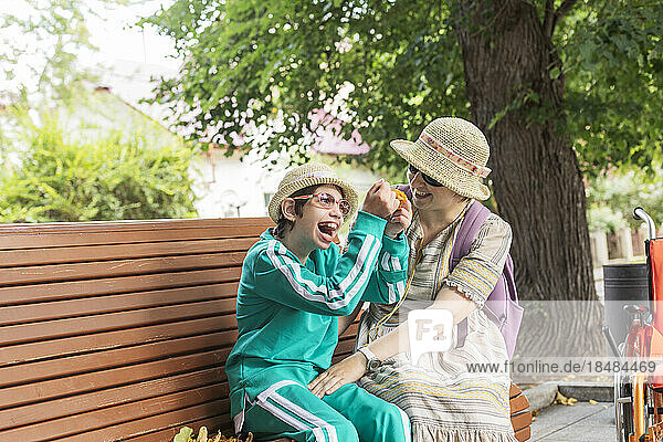 Daughter with disability enjoying by mother sitting on bench