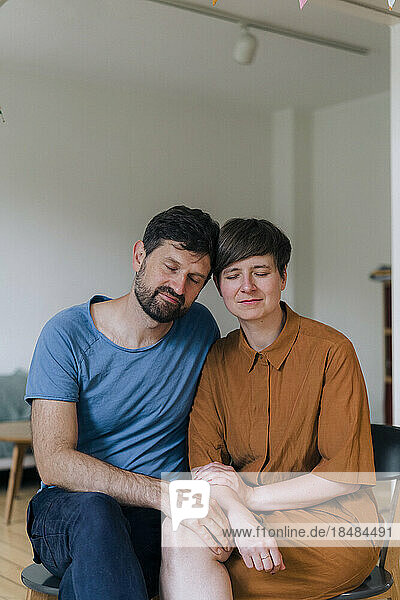 Mature couple with eyes closed sitting at home