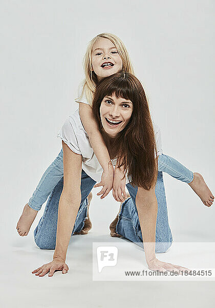 Verspielte Mutter und Tochter haben Spaß vor weißem Hintergrund