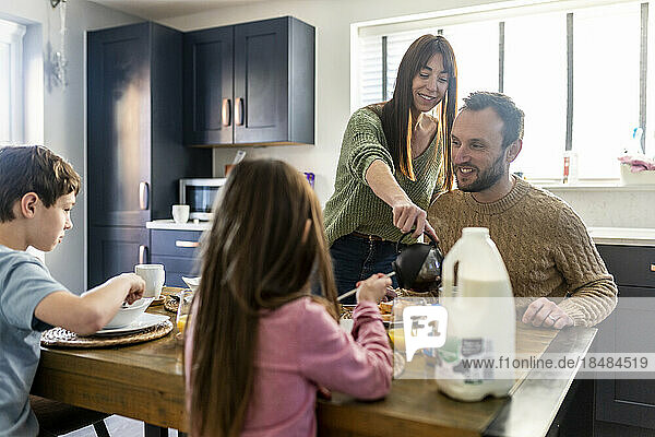 Glückliche Männer und Frauen frühstücken mit Kindern zu Hause