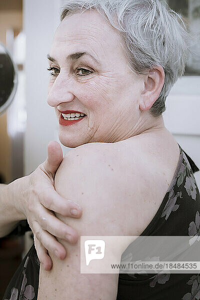 Smiling senior woman applying cream on hand