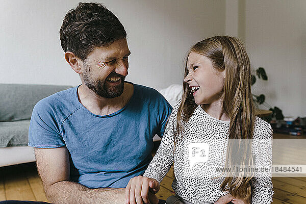 Girl enjoying with father sitting in living room
