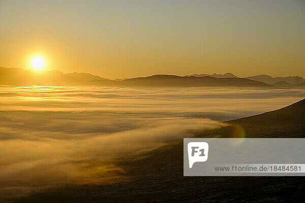 Scenic view of landscape with fog at sunrise