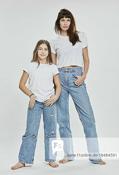 Selbstbewusste Mutter und Tochter stehen vor weißem Hintergrund