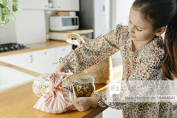 Girl with reusable bags on kitchen island at home