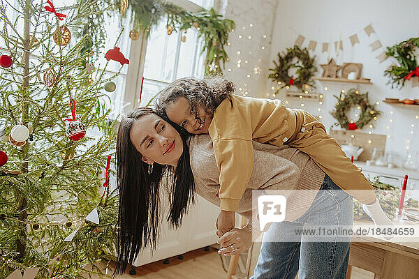 Happy mother giving piggyback ride to daughter at Christmas