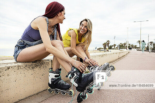 Happy women wearing inline skates at promenade