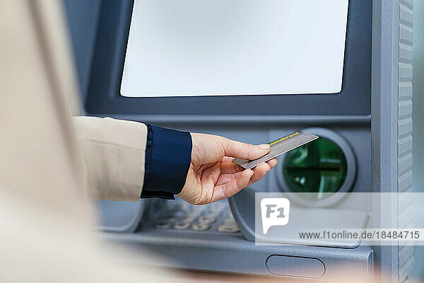 Hand einer Geschäftsfrau mit Kreditkarte am Geldautomaten