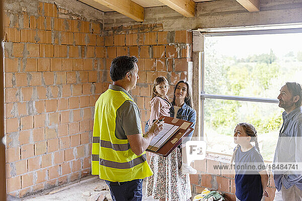 Architect having discussion with family at construction site