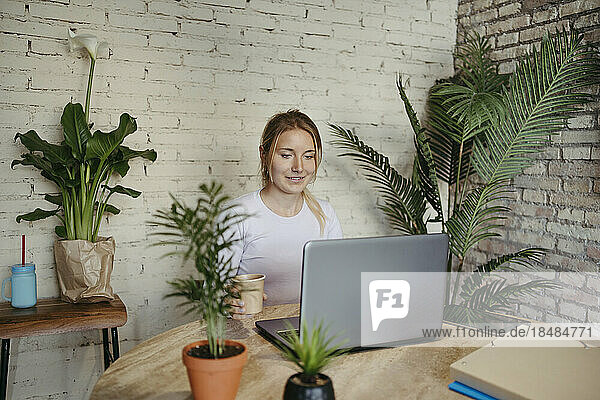 Smiling businesswoman working on laptop at office