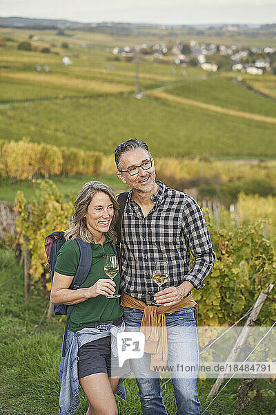 Thoughtful couple with wineglasses standing on hill