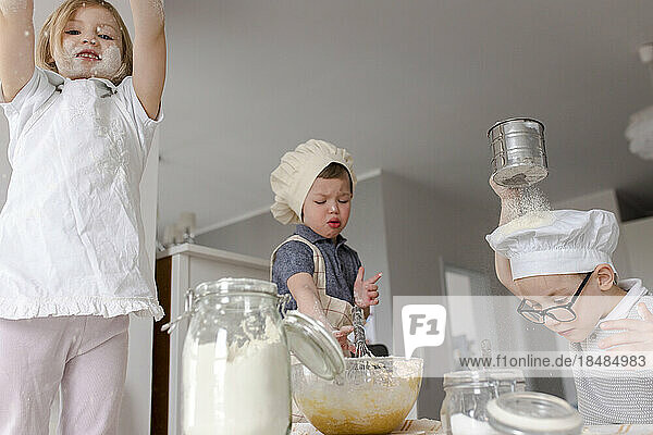 Girl with brother preparing dough in kitchen