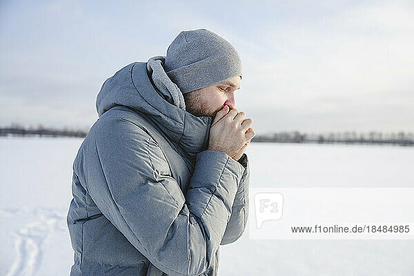 Man wearing knit hat warming hands in winter