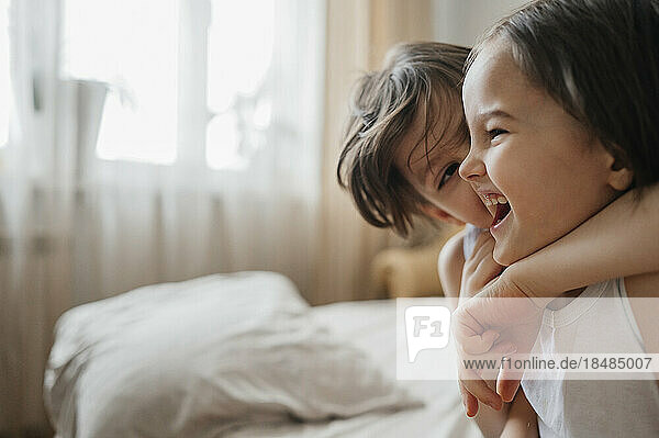 Boy hugging brother on bed at home