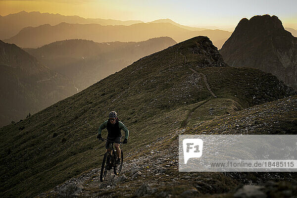 Mountain biker riding bicycle at sunset