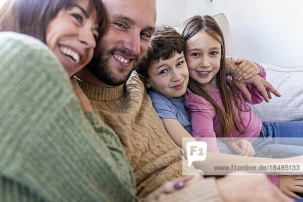 Happy woman embracing family on sofa at home