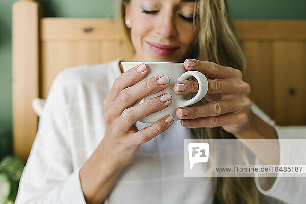 Woman with coffee cup in bed at home