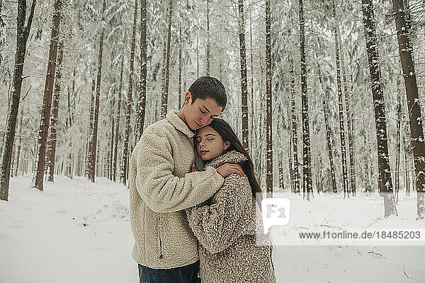 Teenager-Freund umarmt Freundin im verschneiten Wald