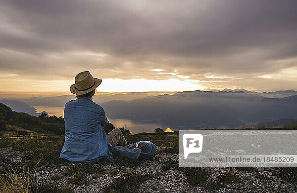 Reife Frau mit Hut sitzt auf dem Berg