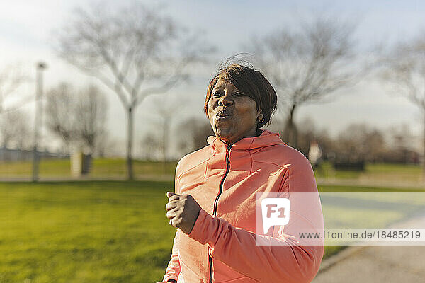 Senior woman jogging in park on sunny day