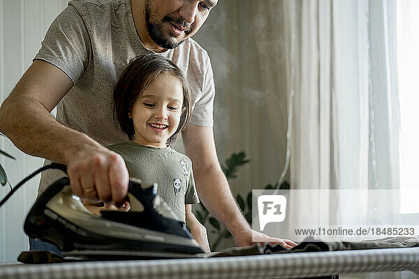 Vater und Sohn bügeln zu Hause Kleidung