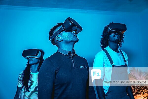 Gruppe junger Menschen mit VR Brille in einem Virtual Reality Spiel in einem blauen Licht  futuristisch oder Wissenschaft  Technologiekonzept