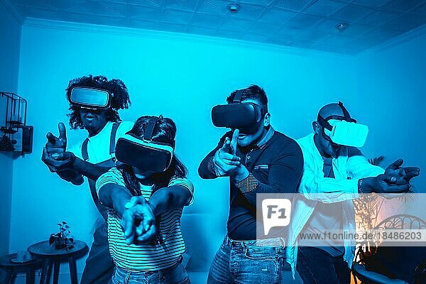 Gruppe junger Leute mit VR Brille in einem Virtual Reality Spiel in einem blauen Licht  zielen mit ihren Händen wie Waffen  futuristisch oder Wissenschaft  Technologiekonzept