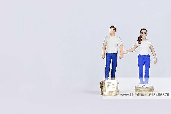 Konzept des geschlechtsspezifischen Lohngefälles mit einem Mann und einer Frau  die auf einer unterschiedlichen Anzahl von Münzen mit Kopierraum stehen