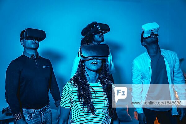 Gruppe junger Menschen mit VR Brille in einem Virtual Reality Spiel in einem blauen Licht  futuristisch oder Wissenschaft  Technologiekonzept erstaunt über den Realismus