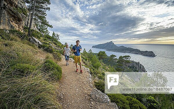 View of mountains and coast with sea  in the evening light  hikers on hike to La Trapa from Sant Elm  in the back island of Sa Dragonera  Serra de Tramuntana  Majorca  Spain  Europe