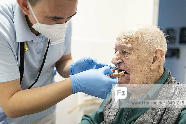 Geriatric nurse sets old mans dentures  Heidelberg  Germany  Europe