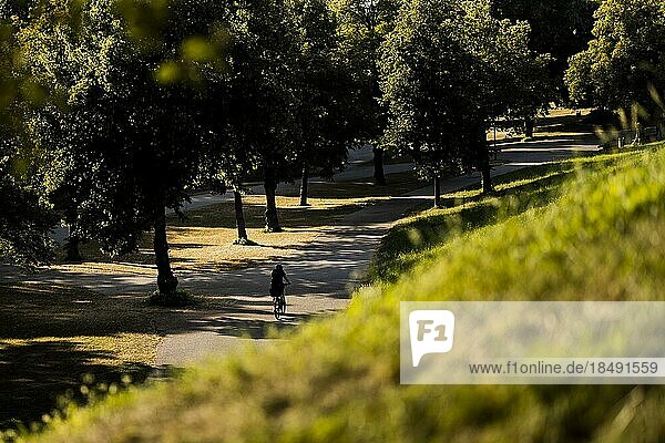 A woman rides her bike through the Olympic Park in Munich  22.07.2022.  Munich  Germany  Europe