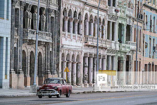 Verblasste Pracht  Stuck  verwitterte Häuser an der Uferpromenade des Malecon  mit rotem Oldtimer  Havanna  Kuba  Westindien  Karibik  Mittelamerika