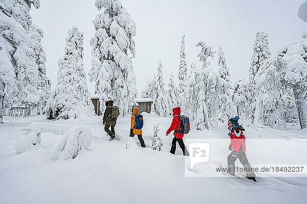 Glückliche Familie beim Spaziergang im verschneiten Wald  Iso Syote  Nördliches Ostbottnien  Lappland  Finnland  Europa